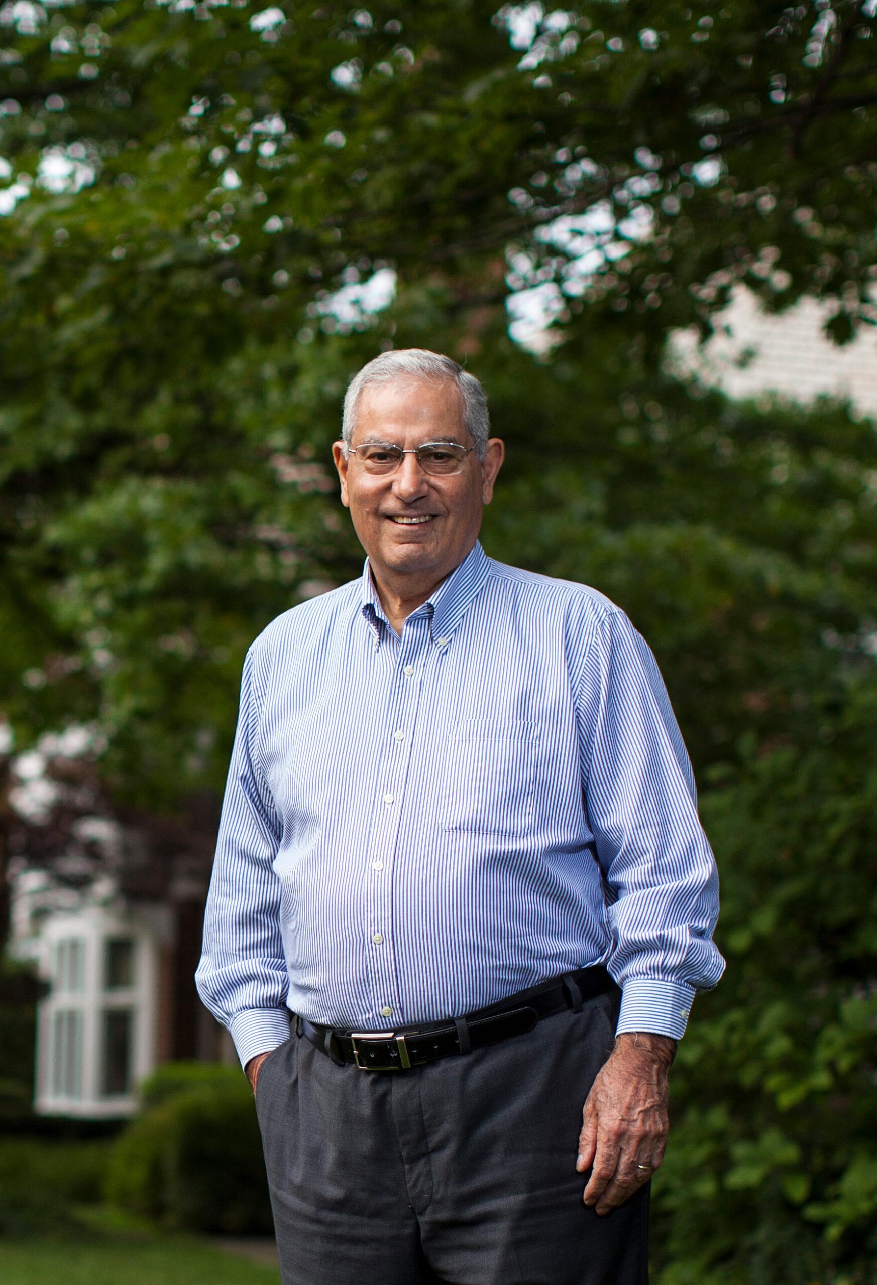 Dr. Faramarz Ismail-Beigi portrait with nature background and Dr. Faramarz is dressed up facing the camera and smiling with one hand on the pocket.